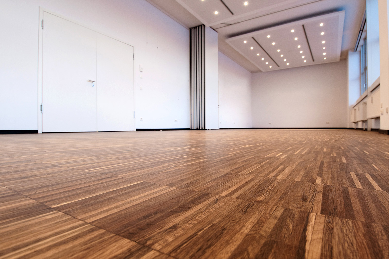 Dunkler Naturholzboden schmückt einen großen leeren Raum, verlegt von Floorstyle (Bogenleger im Raum Wuppertal).