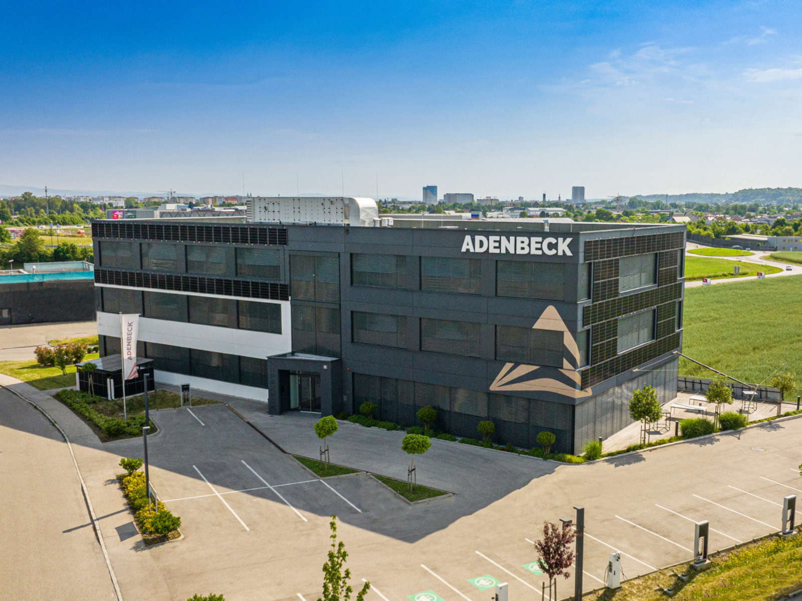 Rechteckiges Bürogebäude mit schwarzer Fassade und der Aufschrift "ADENBECK"