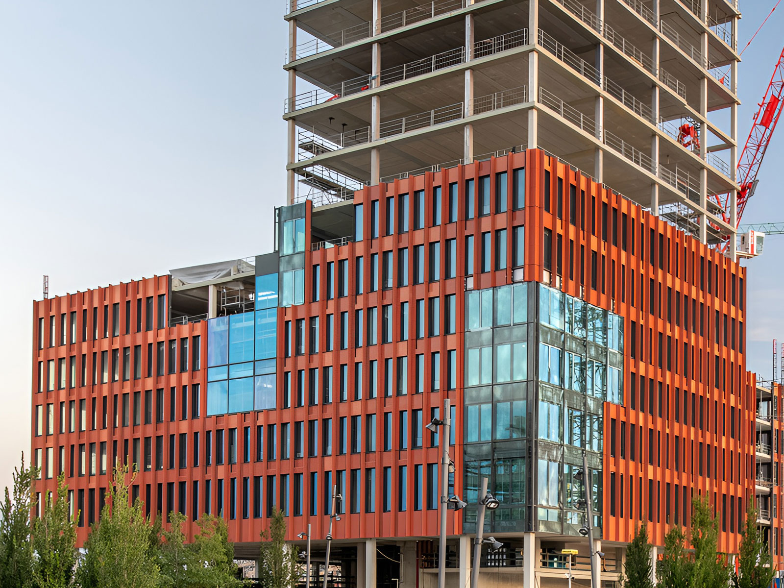 Ein Gebäude mit roter Sockelfassade und anschließendem Tower im Bau
