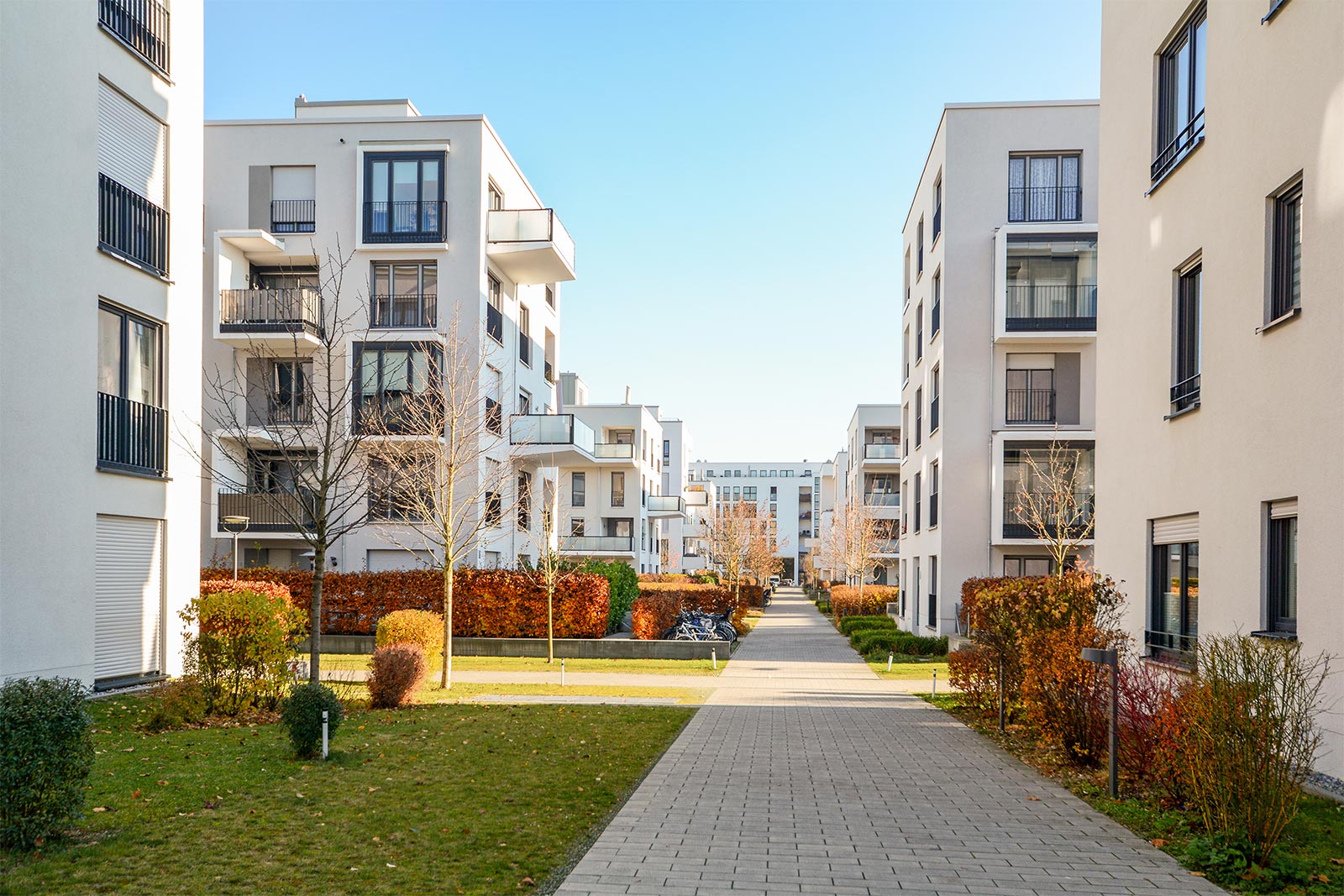 Stockfoto: Ein Weg verläuft durch ein Wohngebiet aus Neubauhäusern. Es verdeutlicht, dass die BayernHeim 2023 1800 bezahlbare Wohnungen abgeschlossen hat.