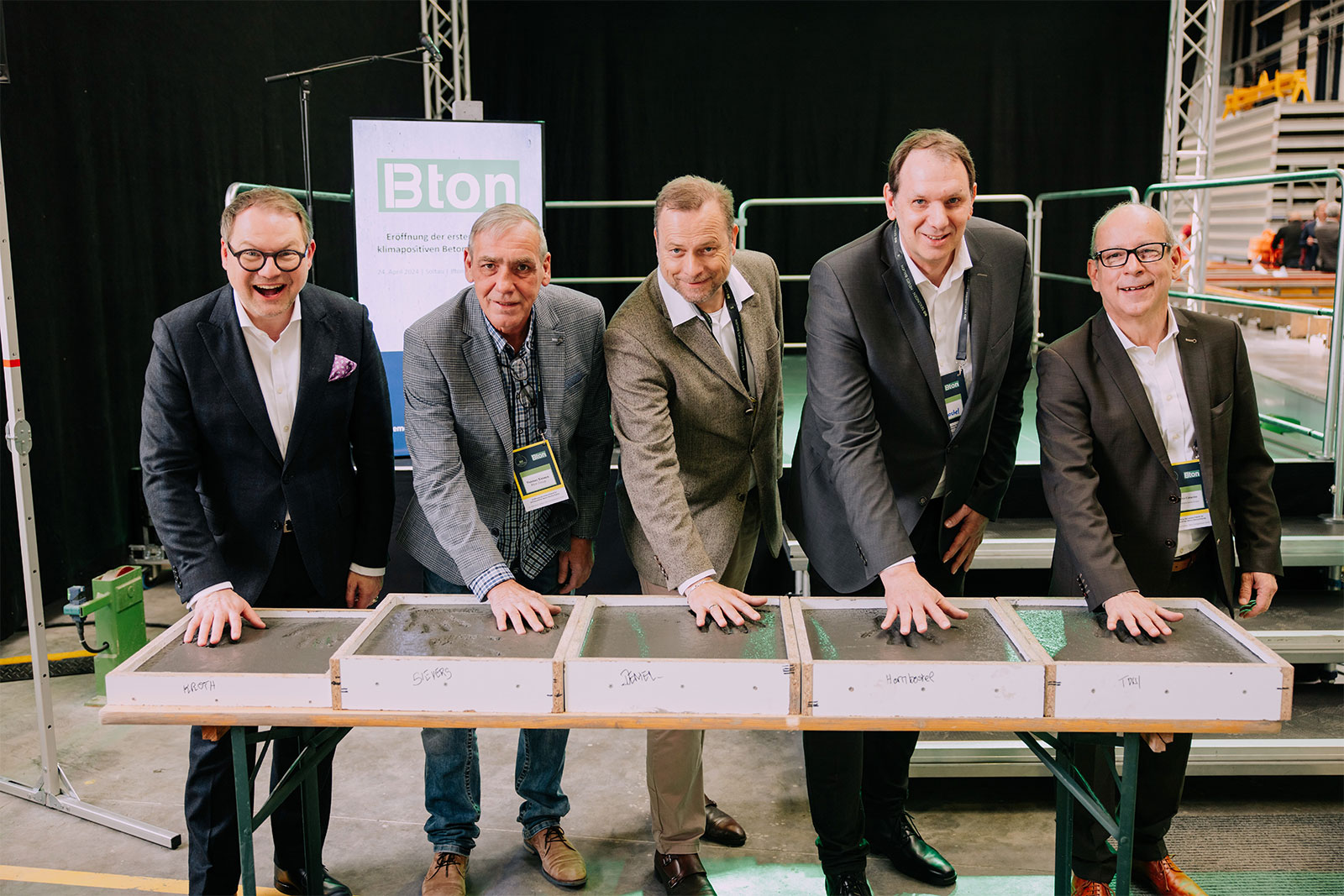 5 Männer drücken bei Eröffnung des Bton Werks in Soltau ihre Hände in klimapositiven Beton.