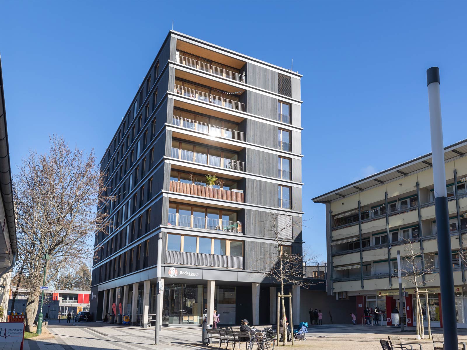 Der Neubau BUGGI 52 in Freiburg aus der Froschperspektive. Das achtgeschossige Holzhaus ist aus dunklem Holz.