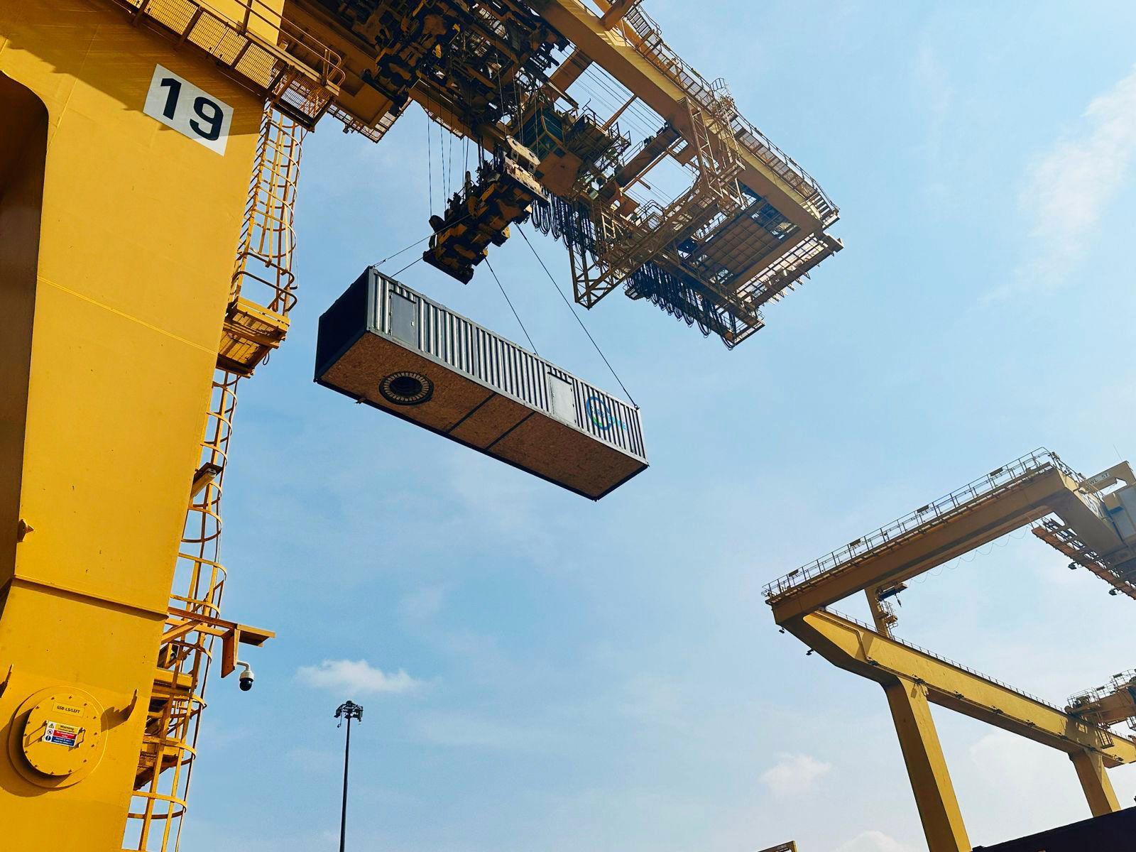 Eine Carbo-FORCE Pyrolyseanlage als Container wird von einem gelben Kran gehoben.