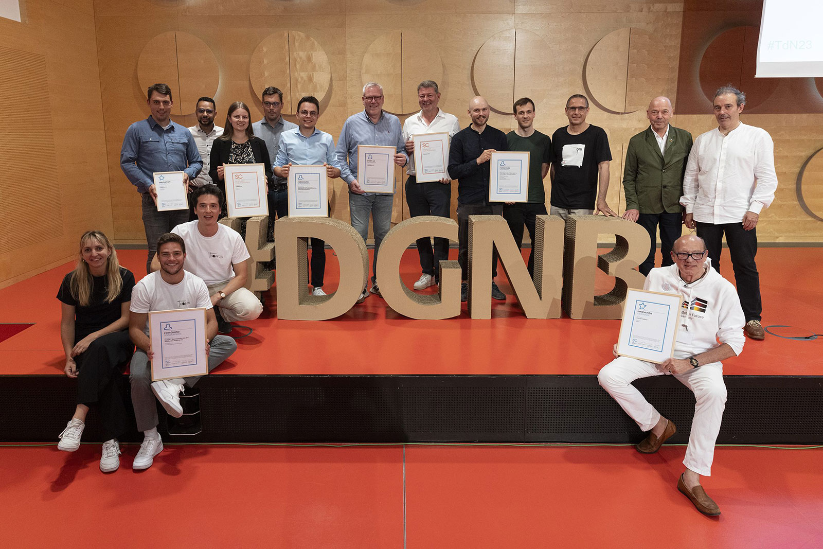 Foto vieler Personen mit Urkunden. In der Mitte des Bildes sind große Buchstaben aus Pappe "#DGNB"