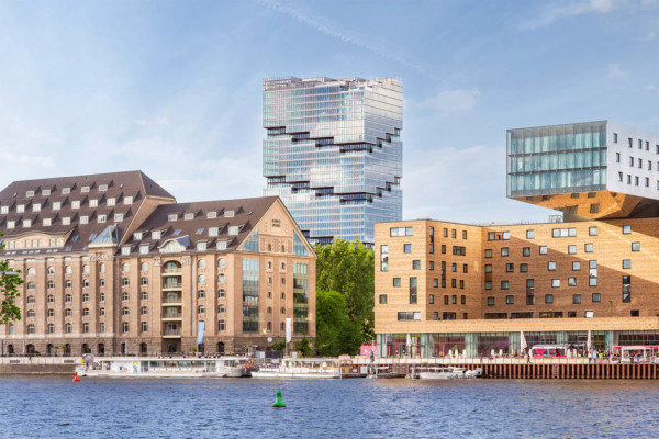 Der Edge Tower in Berlin ragt hinter Wohnhäusern mit seiner Glasfassade hervor.