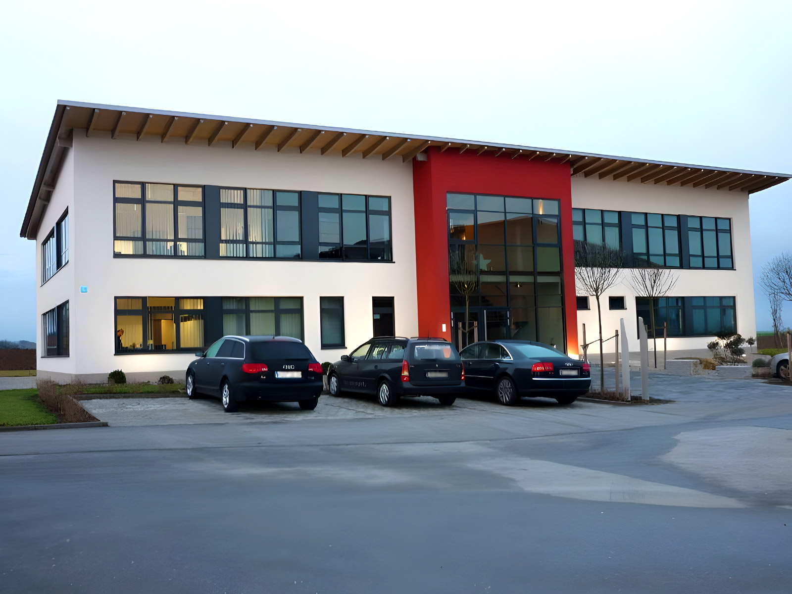 Das Profilbild der Josef Erl Hoch- und Tiefbau GmbH (Erl Bau) in Osterhofen im Raum Deggendorf zeigt ein fertiges modernes Gebäude mit weiß-roter Fassade.