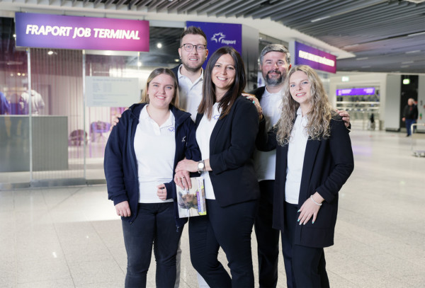 Vor dem Fraport Job Terminal stehen 5 Mitarbeiter, die in die Kamera lachen.