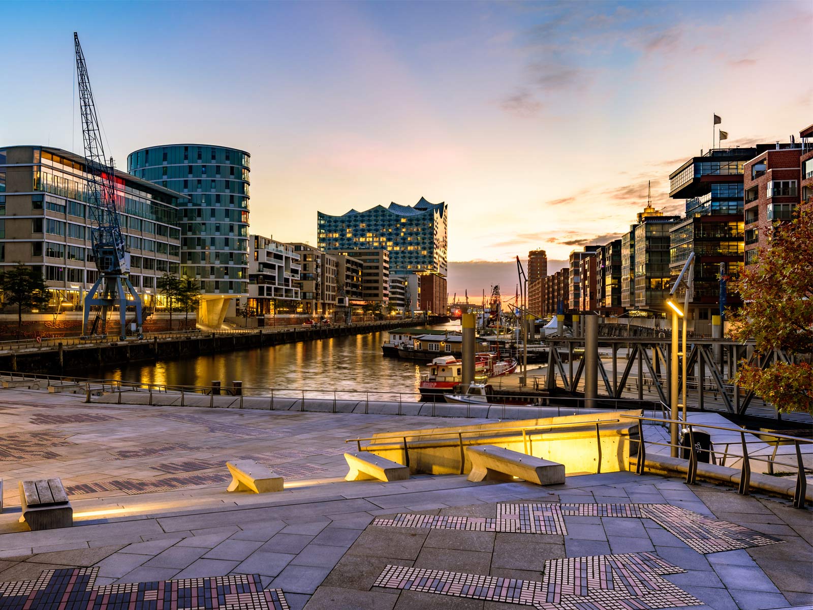 Die Hamburger HafenCity bei Sonnenuntergang. Die sonne geht hinter dem Quartier, das ein neues Quartiersmanagement bekommt, unter.