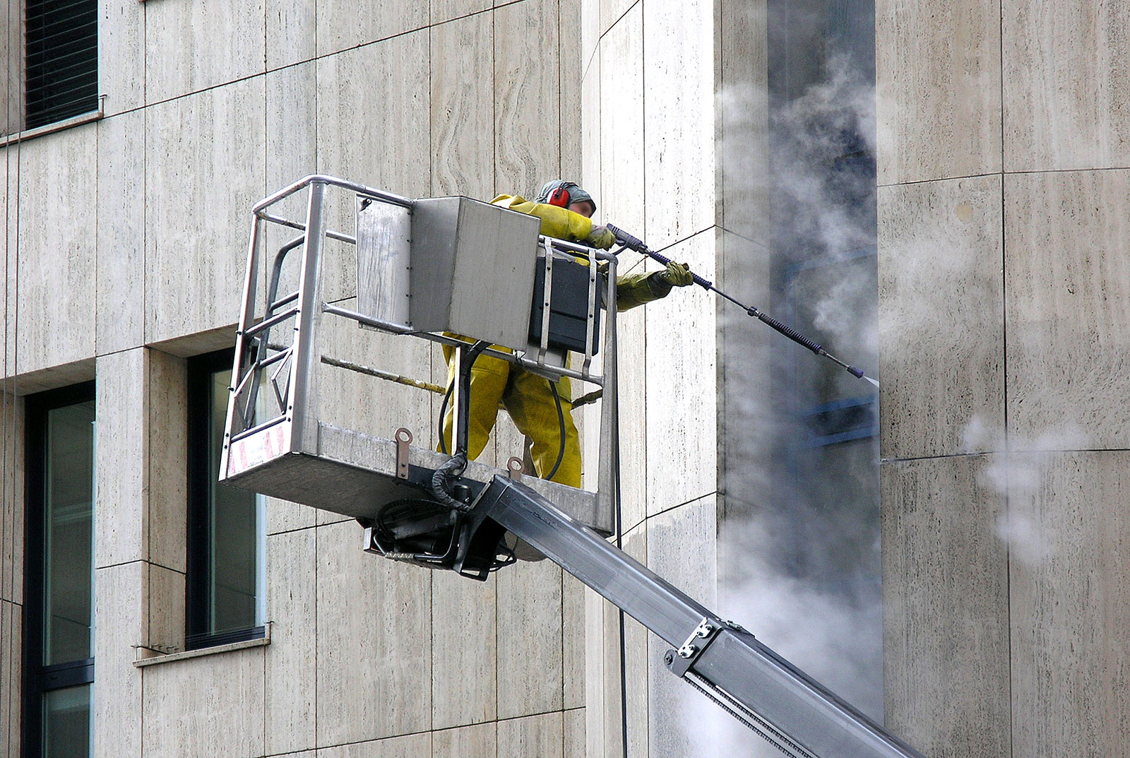 Mitarbeiter von HSG Gebäudeservice reinigt auf einer Hebebühne eine Fassade.