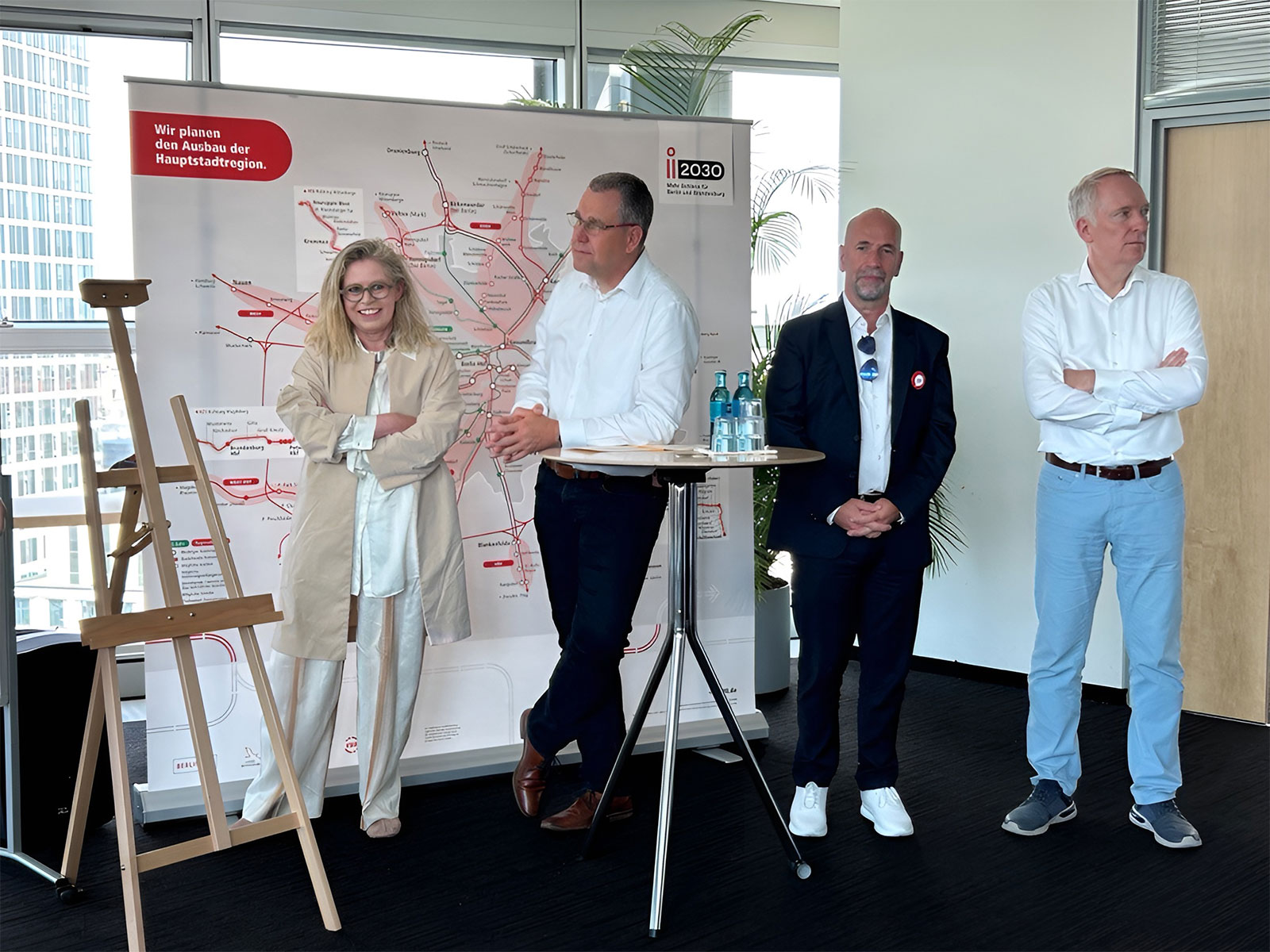 4 Personen stehen beim i2030 Aktionstag vor einem Banner, das das Schienennetz zeigt.