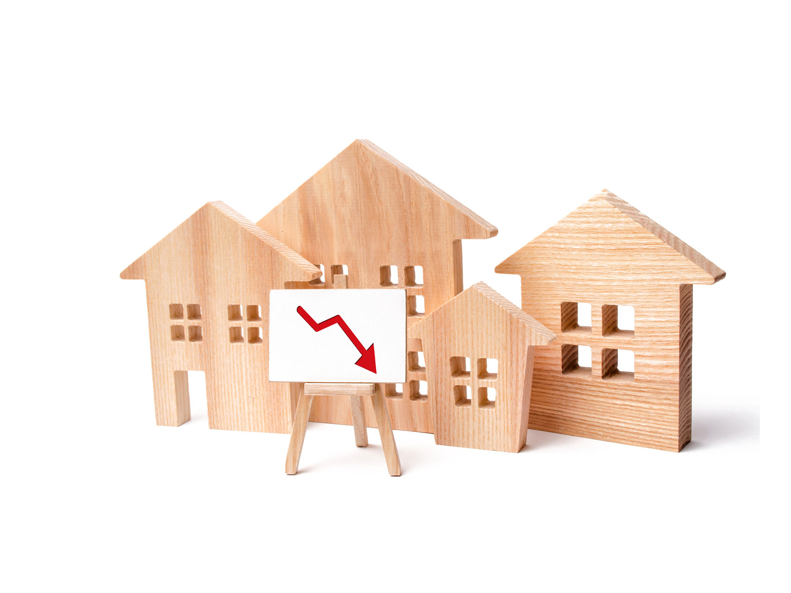 4 Miniaturhäuser aus Holzscheiben, vor der eine Staffelei steht. Auf dem Bild ist ein Abwärtspfeil, der die Preissenkungen des Immobilienpreisindex 2023 verdeutlicht.