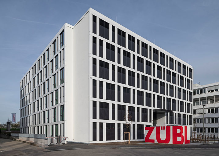 Das Foto des Innovation Center Stuttgart zeigt das blockartige Gebäude mit heller Fassade und abgedunkelten Fensterfronten. Davor sticht der Schriftzug "Züblin" direkt ins Auge.