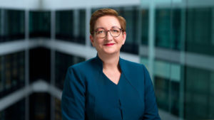 Portrait von Klara Geywitz. Sie hat kurze rot-braune Haare, ein freundliches Lächeln und eine runde Brille auf.