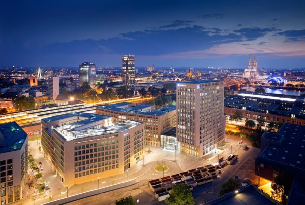 Die fertigen und beleuchteten Gebäude der MesseCity Köln bei Dunkelheit. Köln im Hintergrund