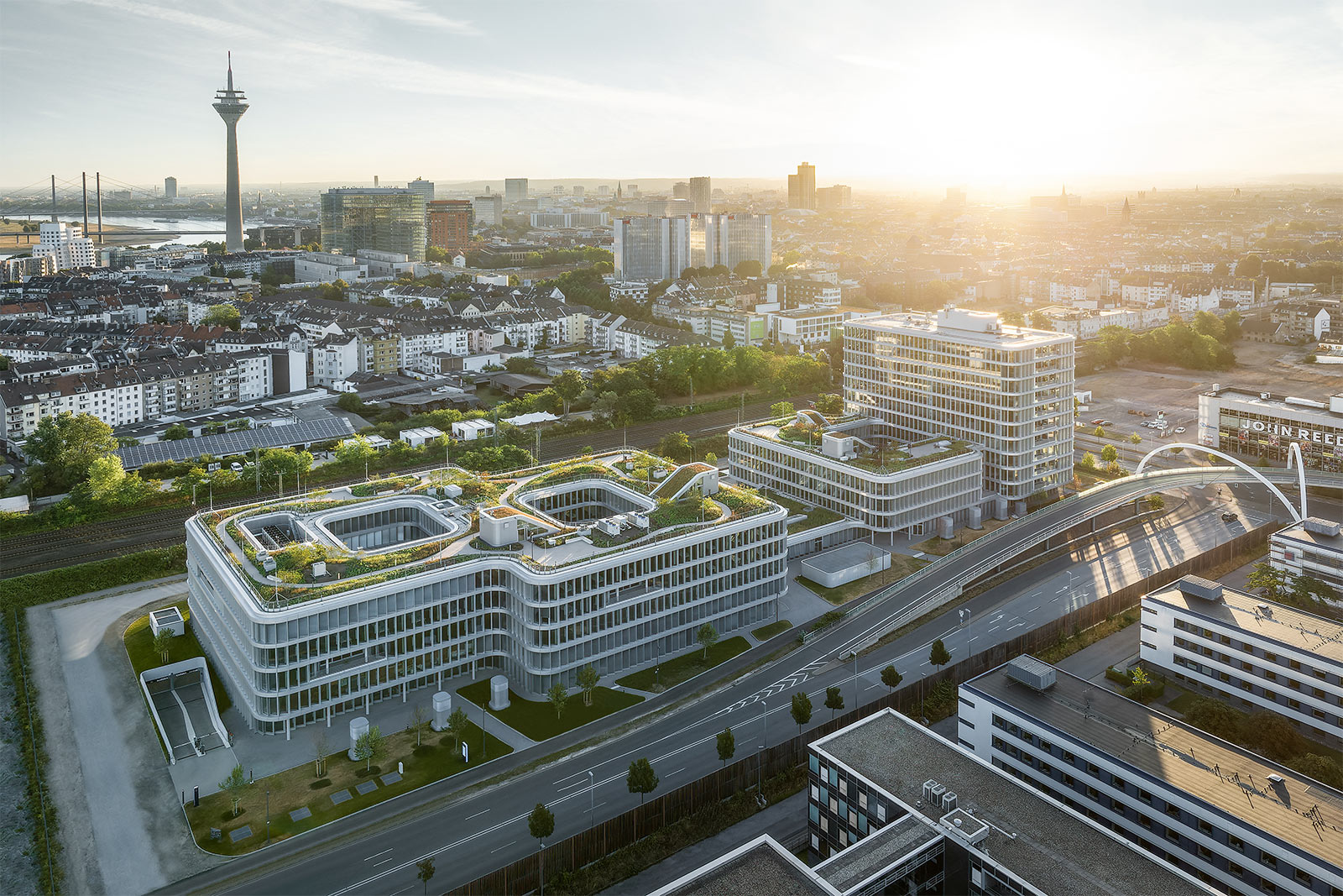 Visualisierung WPP Campus: Luftbild des WPP Headquarters Mizal in Düsseldorf. Es besteht aus zwei Gebäuden, die im ersten Stock miteinander verbunden sind. Eines sieht aus wie eine liegende, eckige Acht. Das zweite besteht aus zwei Teilen: Ein vierstöckiger und ein elfstöckiger Teil
