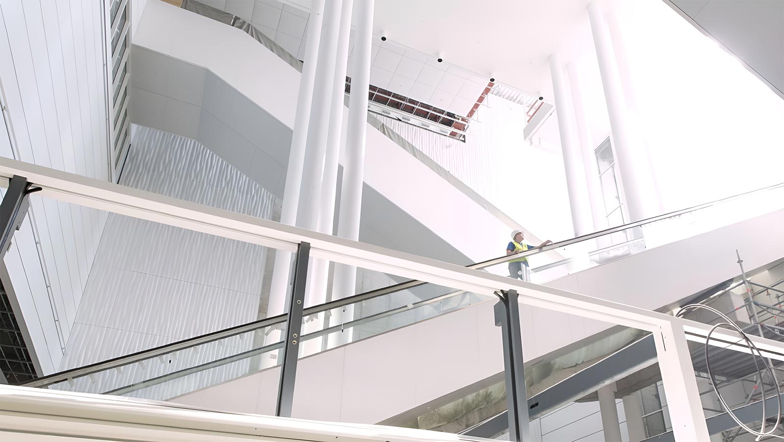 Zwei Rolltreppen in großer Halle von unten. Ein Mann in Warnweste steht in der Mitte des Bildes auf einer der Rolltreppen
