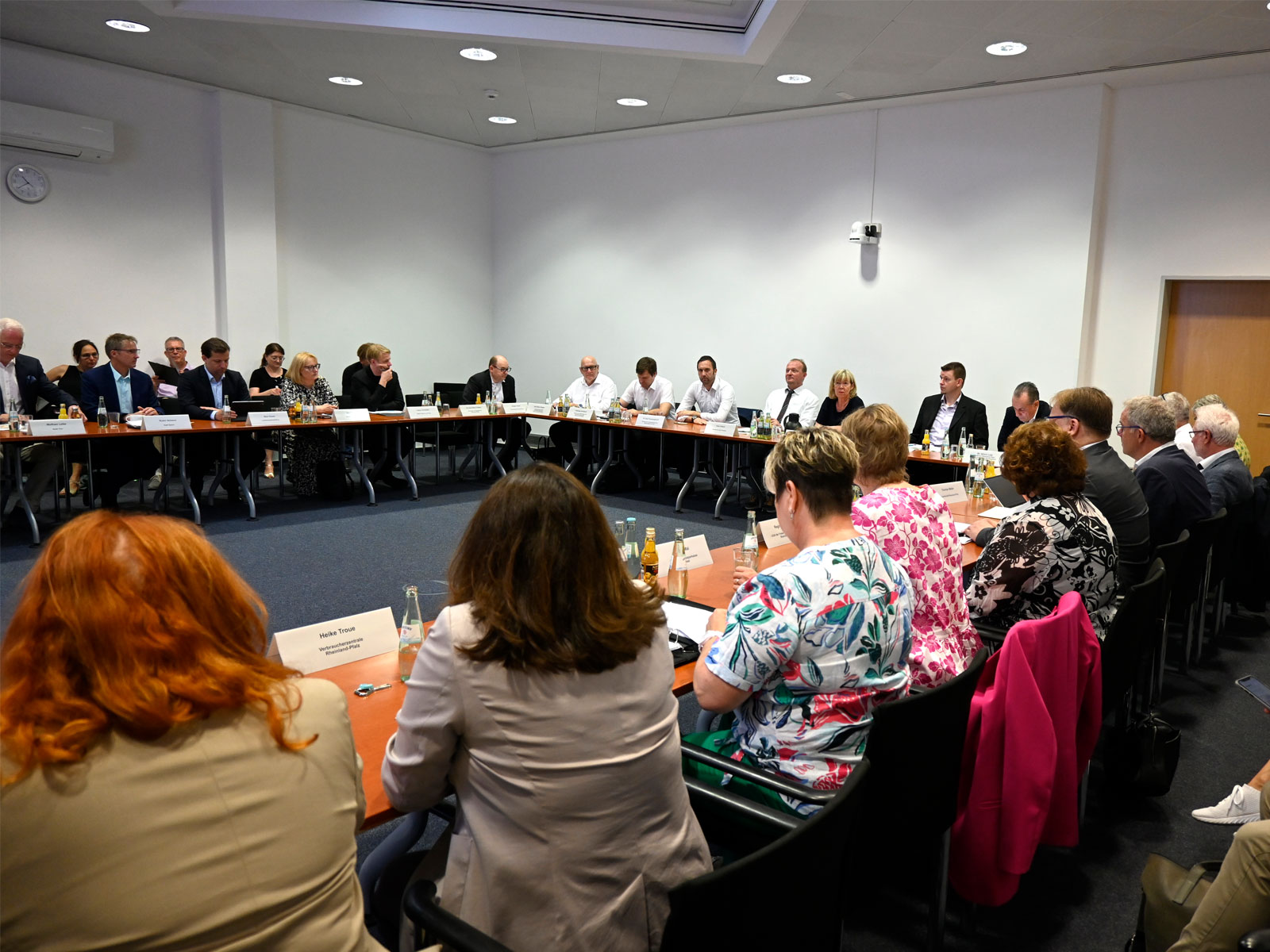 Viele Menschen sitzen an langen Tischen, die ein Gesprächsrunde bilden. Mitglieder vom Bündnis für bezahlbares Wohnen und Bauen beraten über die neue Wohnbauförderung.