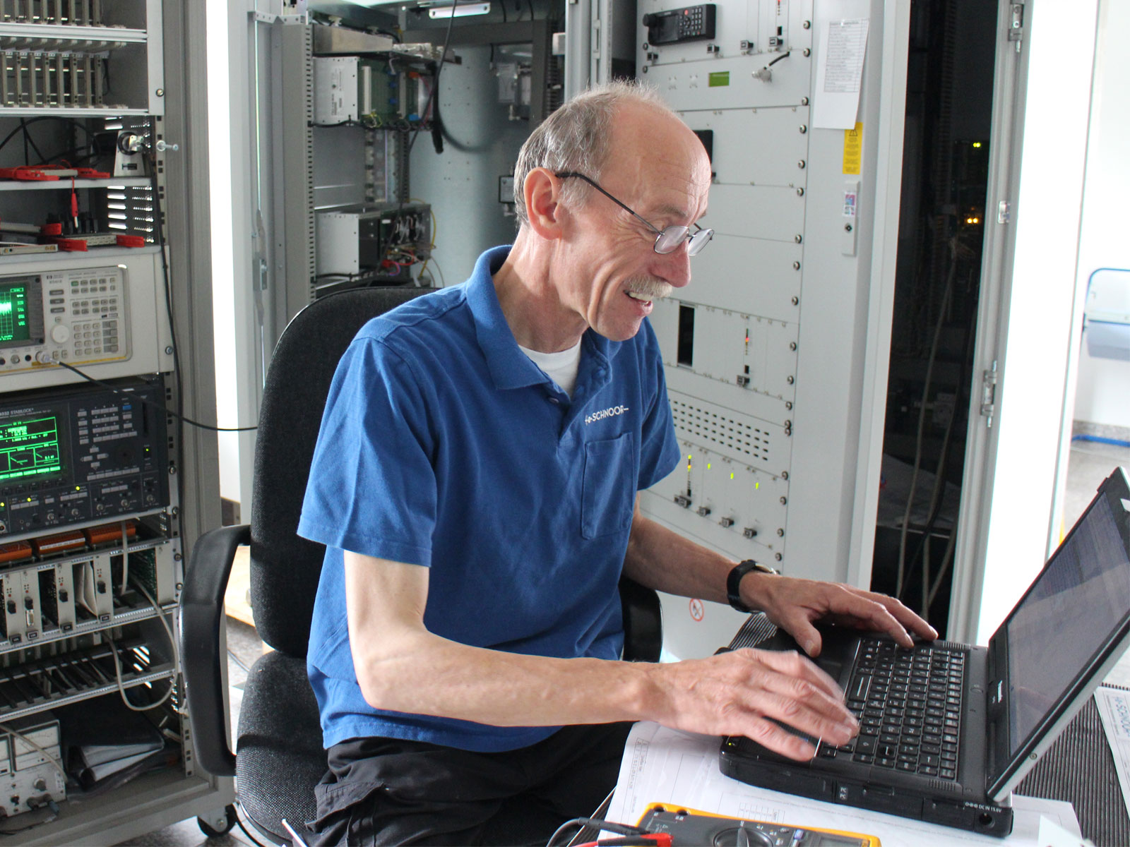 Älterer Mann mit Brille sitzt vor einem Laptop