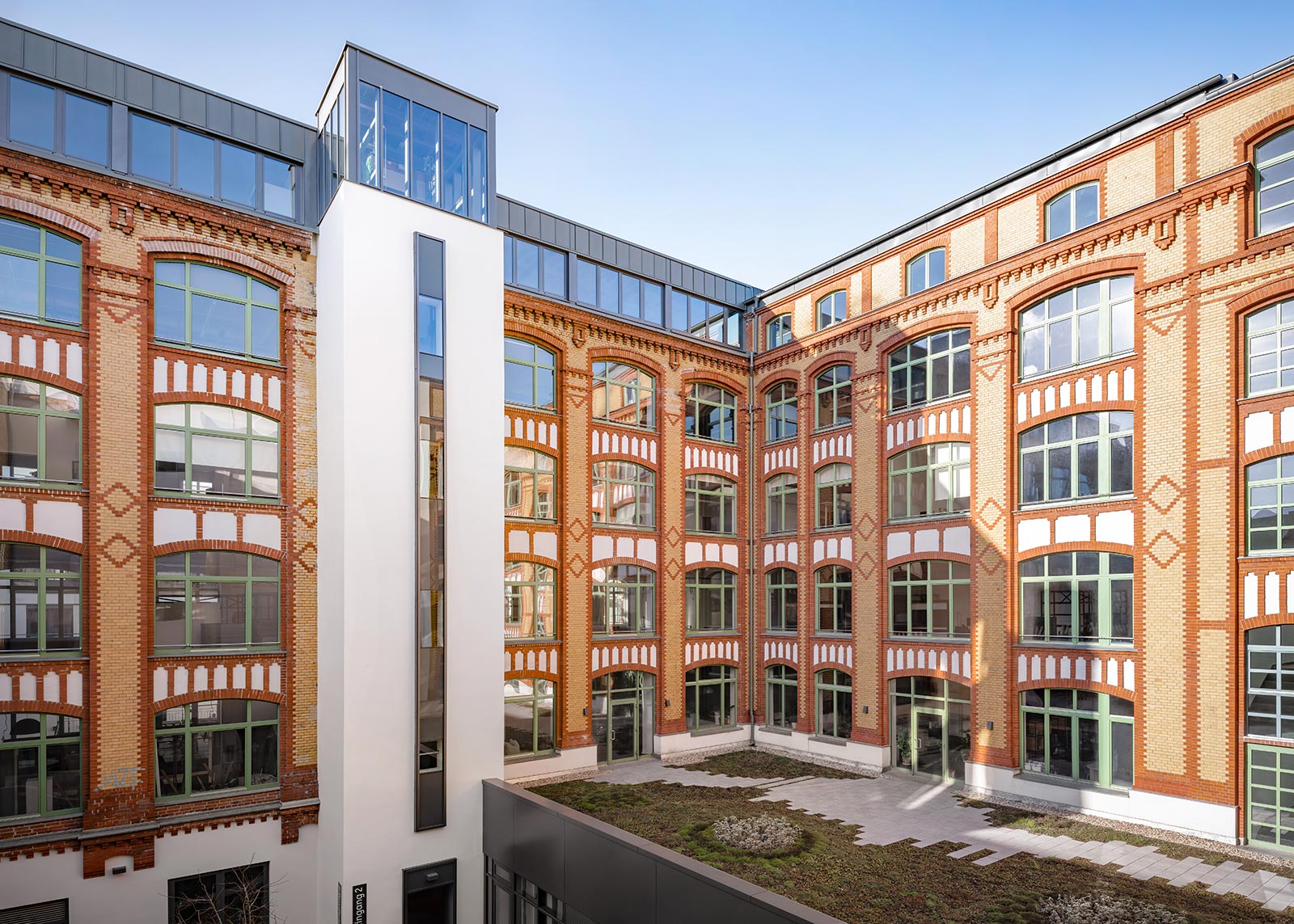 Foto des Quartiers Schreibfederhöfe in Berlin. Eckhaus mit Sicht aus dem Innenhof. Die zierende Klinkerfassade ist in Orange- und Beigetönen gehalten