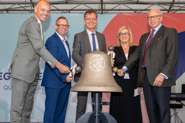 Vier Männer und eine Frau läuten eine Glocke.