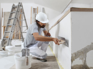 Ein verputzender Handwerker symbolisiert den Gefahr für die Arbeitsplätze vieler Gewerke.