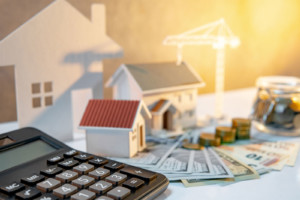 Häuser, Baukran und Geld symbolosieren die notwenigen vergünstigten Kredite für den bau von Sozialwohnungen.